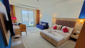 A hotel room with a large bed, a desk with a chair, a sofa, and a TV. - Hotel Boulefkhad (Filfila)