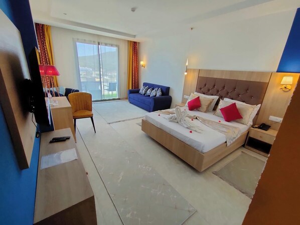 A hotel room with a large bed, a desk with a chair, a sofa, and a TV. - Hotel Boulefkhad (Filfila)