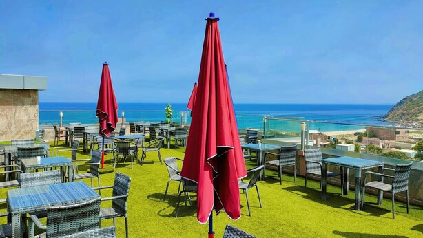 A terrace with outdoor seating and a view of the ocean. - Hotel Boulefkhad (Filfila)