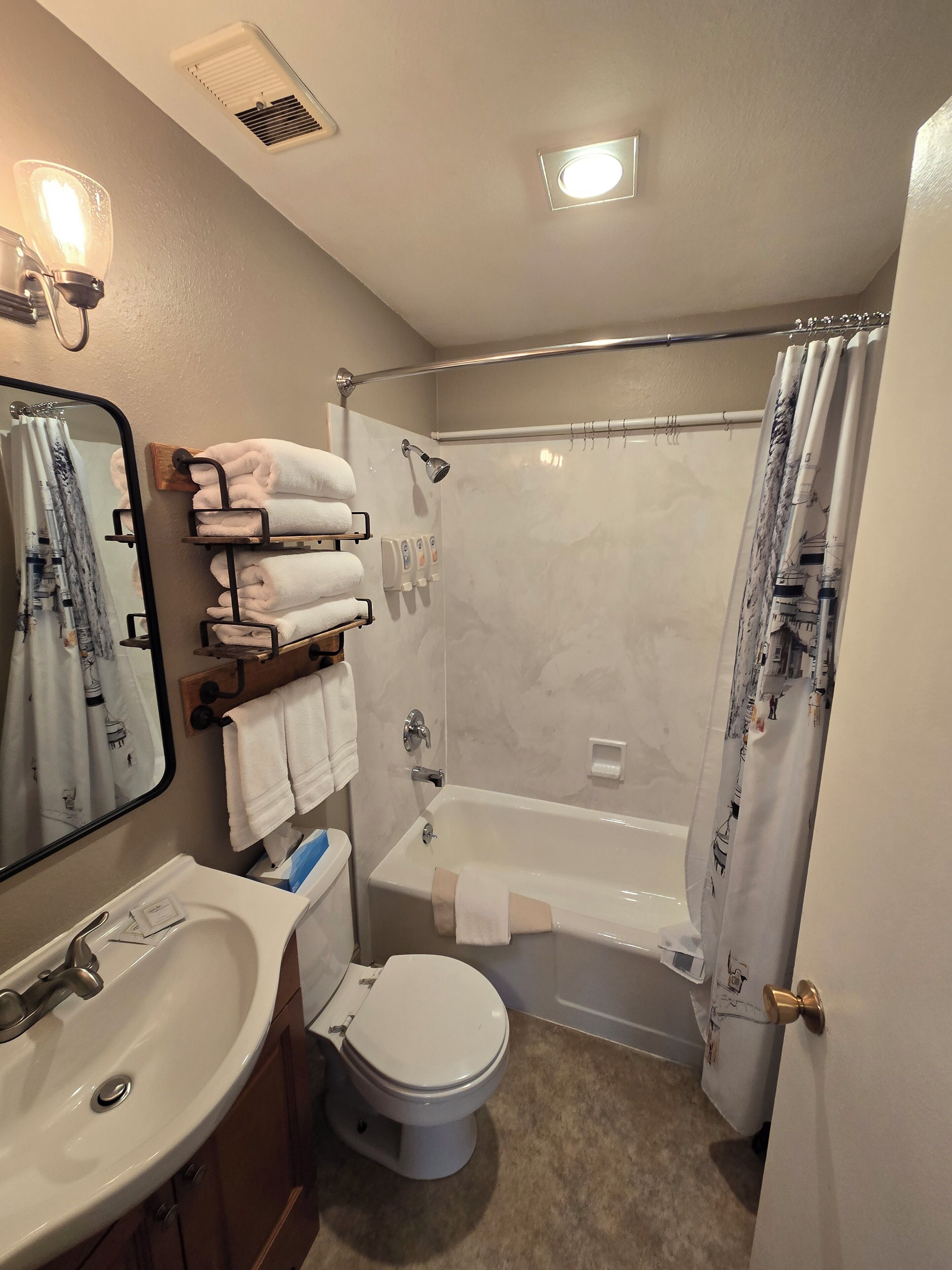 A bathroom with a sink, toilet, and bathtub. There are towels on a rack and a shower curtain.