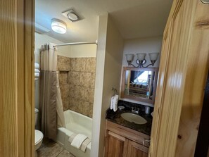 Baño con ducha, inodoro, lavabo y espejo.