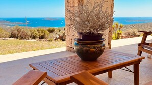 Une table et des chaises en bois sur une terrasse avec vue sur la mer.