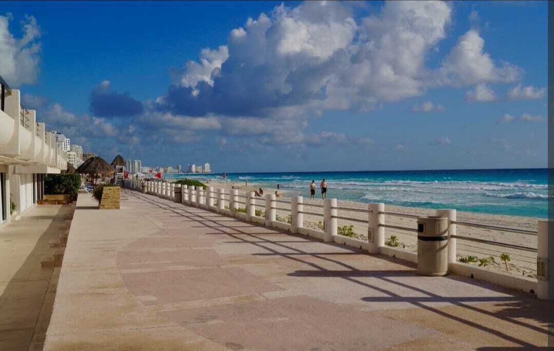En kystpromenade med en belægning af sten, hvide gelændere og udsigt over havet.