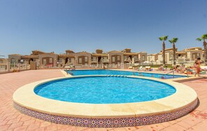 Une grande piscine extérieure entourée d’une terrasse carrelée avec une bordure décorative.