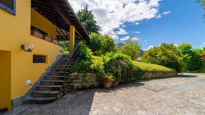 A yellow building with a stone staircase leading to a covered porch.