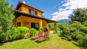 A yellow villa with a patio, outdoor furniture, and lush greenery.