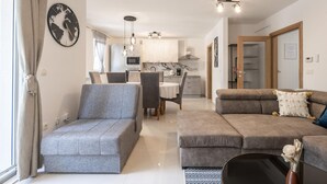 A modern living room with grey sofas, a dining area with a table and chairs, and a kitchen in the background. - Apartment Magic Moments (Rijeka)