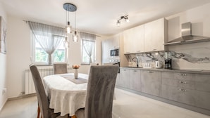 A modern kitchen with grey cabinets, a marble backsplash, and a built-in oven. - Apartment Magic Moments (Rijeka)