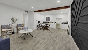 A spacious room with a dining area, a sofa with patterned cushions, and a potted plant. - Spacious 9-bedroom house in Las Vegas 15 min to The Strip! (Las Vegas)