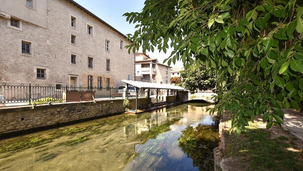 Un canale fiancheggiato da edifici in pietra da un lato e da una galleria coperta dall'altro.