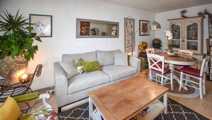 Un soggiorno con divano, tavolino in legno, tavolo da pranzo con sedie e una credenza con ante in vetro.