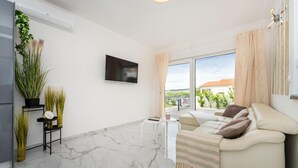 A modern living room with a sofa, a TV, and a balcony with a view. - Beautiful home in Maslenica with WiFi (Maslenica)