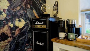 Une cuisine équipée d’un amplificateur Marshall, d’une machine à café Keurig et ornée d’une tapisserie à motifs floraux.