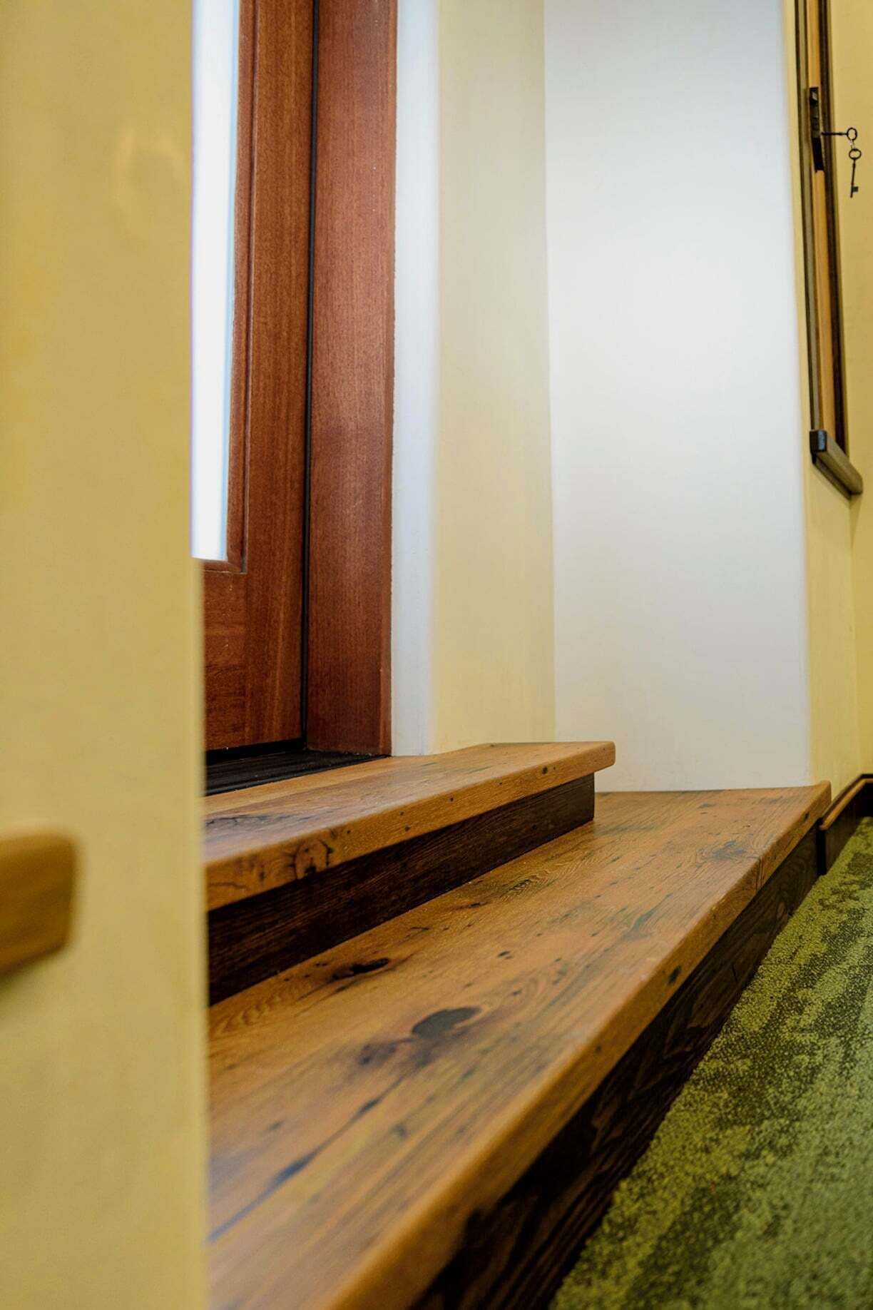 A wooden staircase leading to a door with a keyhole.