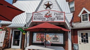 A restaurant with a sign advertising Cuban sandwiches and rum cakes.