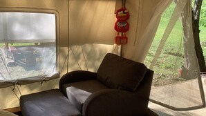 A cozy interior with a cushioned seating area, a window with a view of greenery, and a red fire extinguisher mounted on the wall.