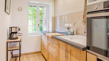 A compact kitchen with wooden cabinets, a built-in oven, and a window providing natural light.