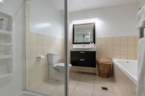 A modern bathroom with a glass shower enclosure, a toilet, a sink with a mirror above, and a bathtub. - Spacious Central Executive Apartment
4 Bedroom, 2 Bathroom with amazing views (Queenstown)