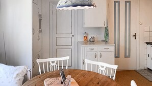 A dining area with a wooden table, white chairs, a pendant light, and a kitchen area with cabinets and a door. - Awesome home in Alsterbro with WiFi (Alsterbro)