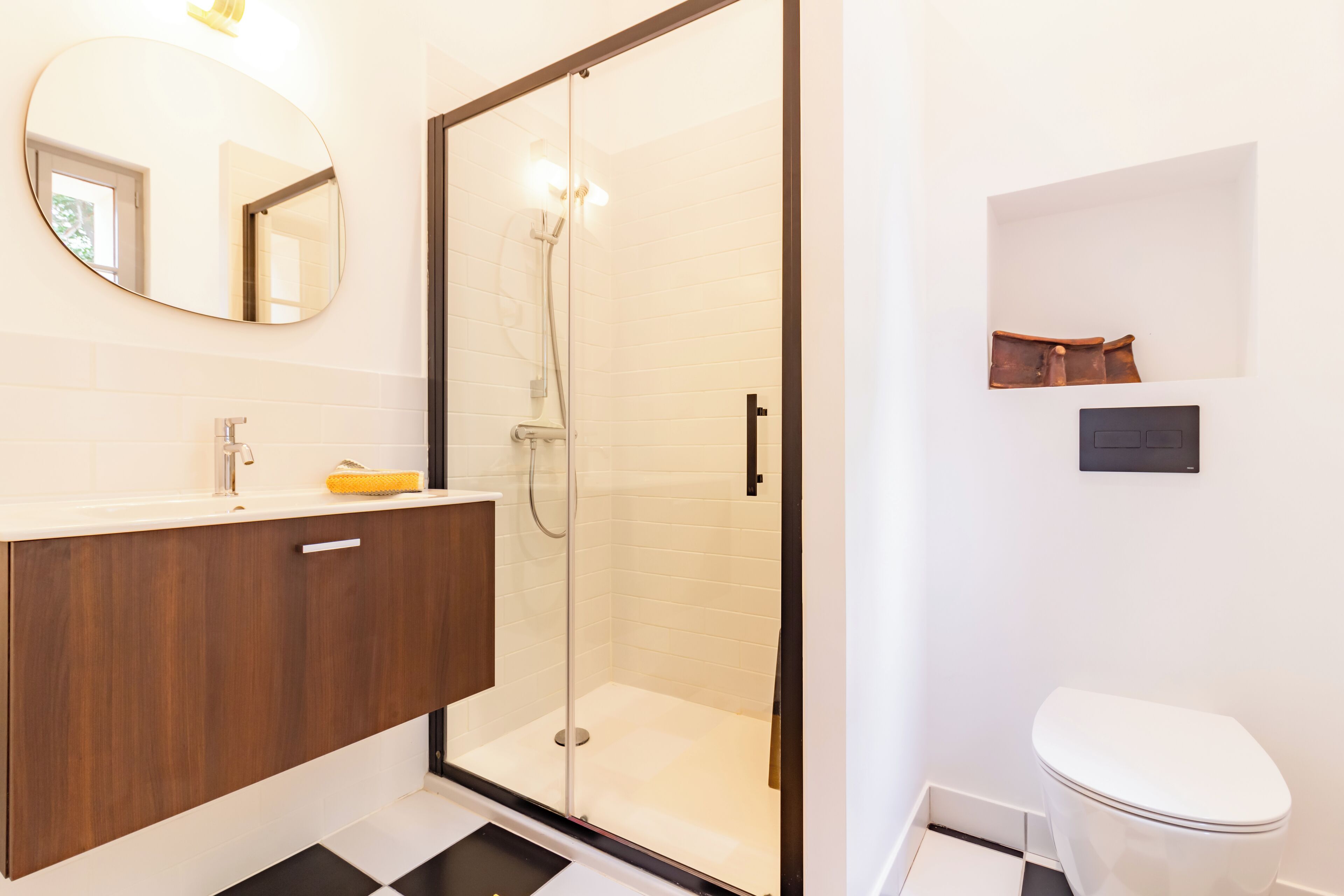 A modern bathroom with a glass-enclosed shower, a wooden vanity, and a white toilet.