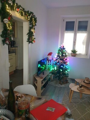 Ein gemütliches Wohnzimmer mit Weihnachtsbaum, Fernseher und Essbereich.