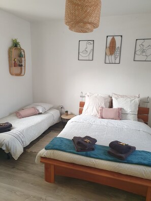 Ein Schlafzimmer mit zwei Betten, einer gewobenen Lampe und Wandbildern.