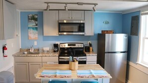 A compact kitchen with a microwave, stove, and refrigerator, a coffee bar sign, and a beach-themed tablecloth. - Seaside Social - Steps to Wally's, Goat, L Street (Hampton)