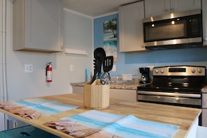A kitchen with a wooden countertop, a stainless steel microwave, a stove, and a fire extinguisher. - Seaside Social - Steps to Wally's, Goat, L Street (Hampton)