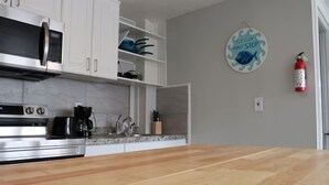 A kitchen with white cabinets, a microwave, a coffee maker, and a wooden countertop. - Seaside Social Deluxe - Steps to Wally's, Goat (Hampton)