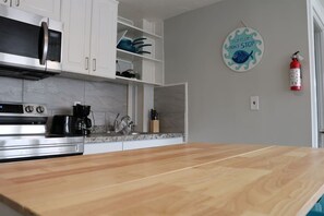 A kitchen with white cabinets, a microwave, a coffee maker, and a wooden countertop.