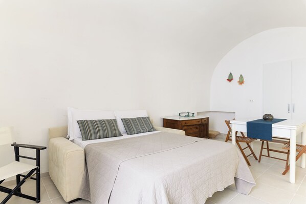 A bedroom with a bed, bedside table, chair, desk, and a small cabinet. - Terrazza Casalicchio by Wonderful Italy (Ostuni)