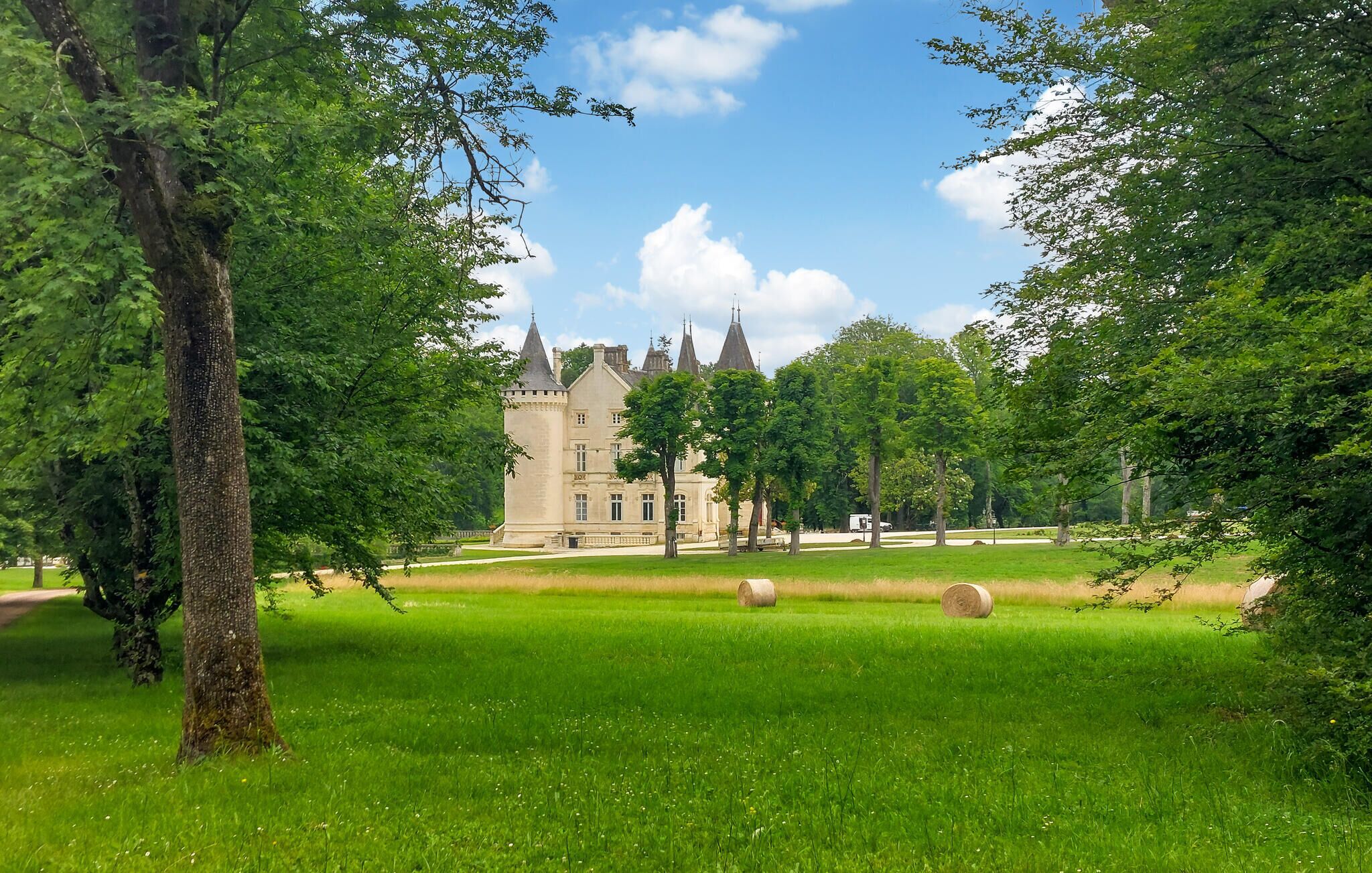 A castle with a tower, surrounded by a well-maintained lawn and trees.