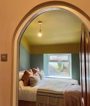A cozy bedroom with a bed, pillows, and a window. - Luxury Boutique Cotswold Cottage with Hot Tub! (Winchcombe)