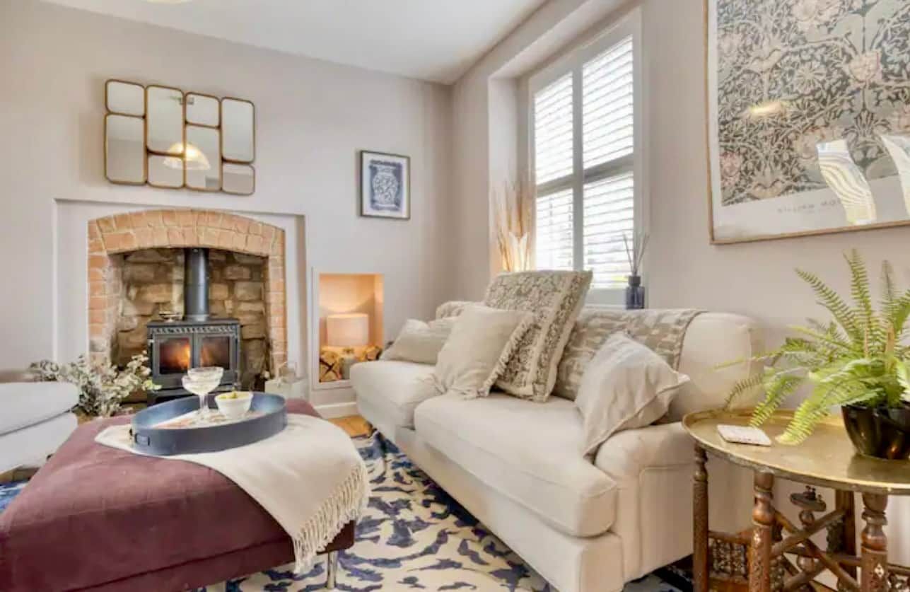 A living room with a fireplace, a sofa, a coffee table, and a potted plant.