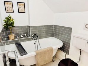 A modern bathroom with a freestanding bathtub, a small potted plant, and a towel rack. - Stunning cotswold, period country house, hot tub, great for extended family (Gloucestershire)