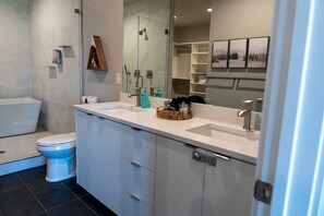 A modern bathroom with a bathtub, toilet, and a large mirror.