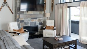 Un salon moderne avec une cheminée en pierre, un téléviseur à écran plat, un grand canapé et une table basse.