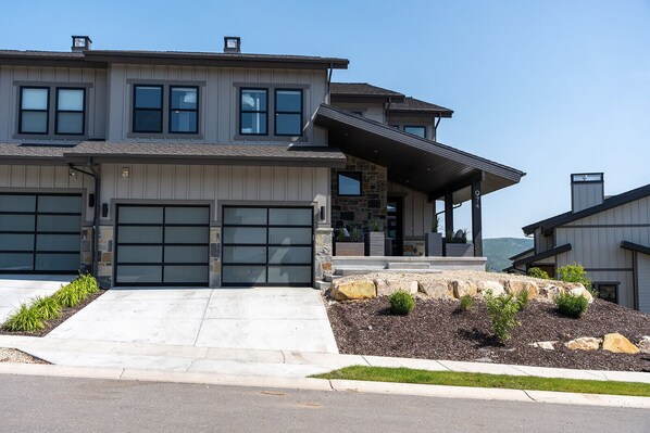 A modern two-story house with a garage, stone facade, and a covered porch.