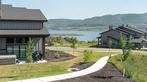 Un quartier résidentiel moderne avec des maisons, un sentier et un lac en arrière-plan.