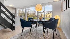A modern dining area with a round table, blue chairs, and a geometric pendant light. - Cozy home in Farsø with WiFi (Farsø)