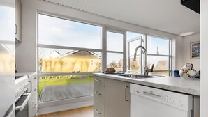 A modern kitchen with large windows, a dishwasher, and a view of a green yard. - Cozy home in Fars ø with WiFi (Farsø)