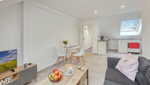Un apartamento moderno con sala de estar, comedor, kitchenette y balcón.