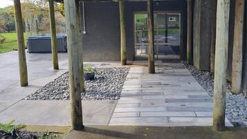 A covered outdoor area with stone flooring and wooden posts, leading to a glass door.