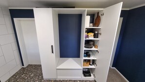 A walk-in closet with a blue door, shelves with various items, and a small step leading to a lower level. - Relax at Stagga Arcadia, tranquil 1 bedroom suite on rural farmlet with spa (Huiroa)