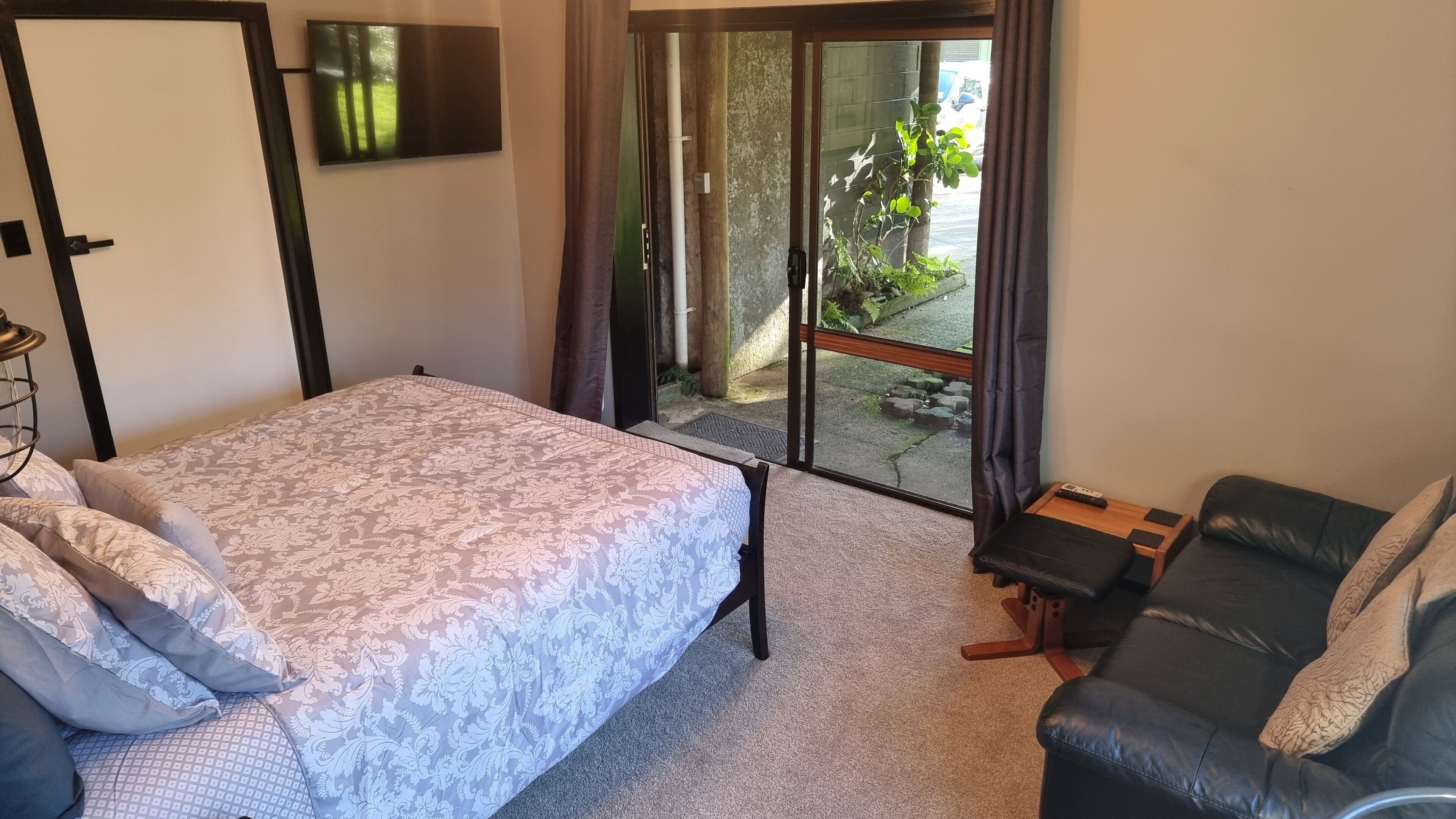 Un dormitorio con cama, sofá, televisión y vistas al exterior.
