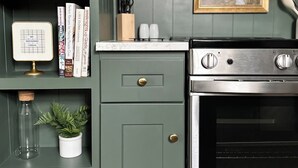 Una cocina con horno integrado, microondas y lavaplatos. Hay libros y utensilios de cocina en los estantes.