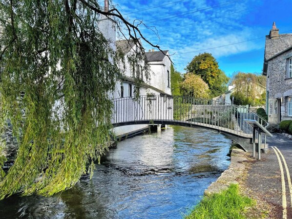 A narrow waterway with a bridge, surrounded by stone buildings and lush greenery.
