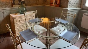 Una mesa redonda de cristal con cuatro sillas, una lámpara de pie verde y un cuadro en la pared.