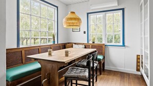 A cozy kitchen with wooden benches, a central island, and large windows with blue trim.