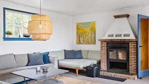 A living room with a sofa, a coffee table, a fireplace, and a window with a view of trees.